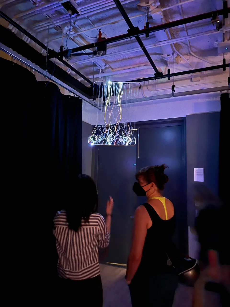 Esther discussing Light Wave with a visitor beneath the illuminated installation